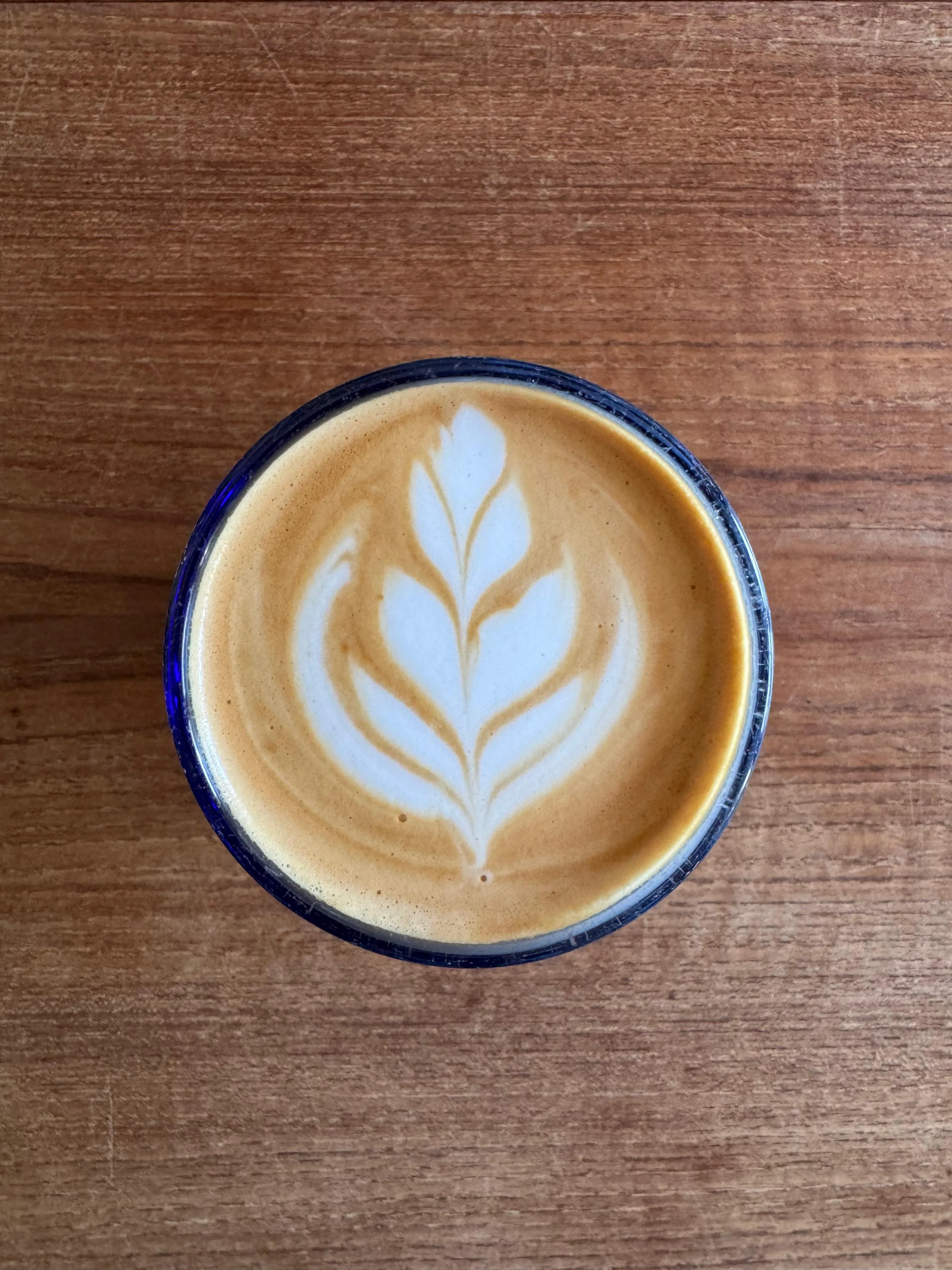 Latte art I poured in a blue cup on a wooden table